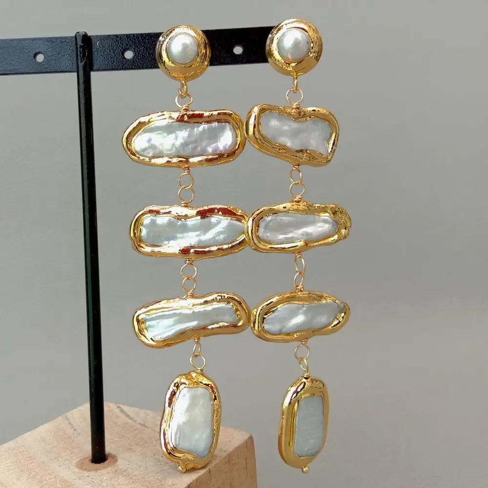 Gold and pearl earrings on a gray background