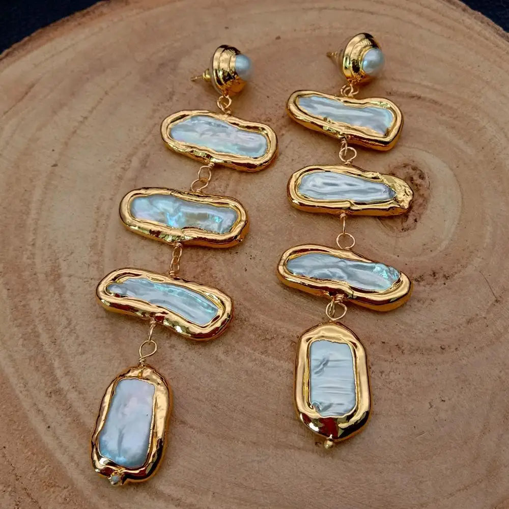 Gold and stone earrings on a wooden surface