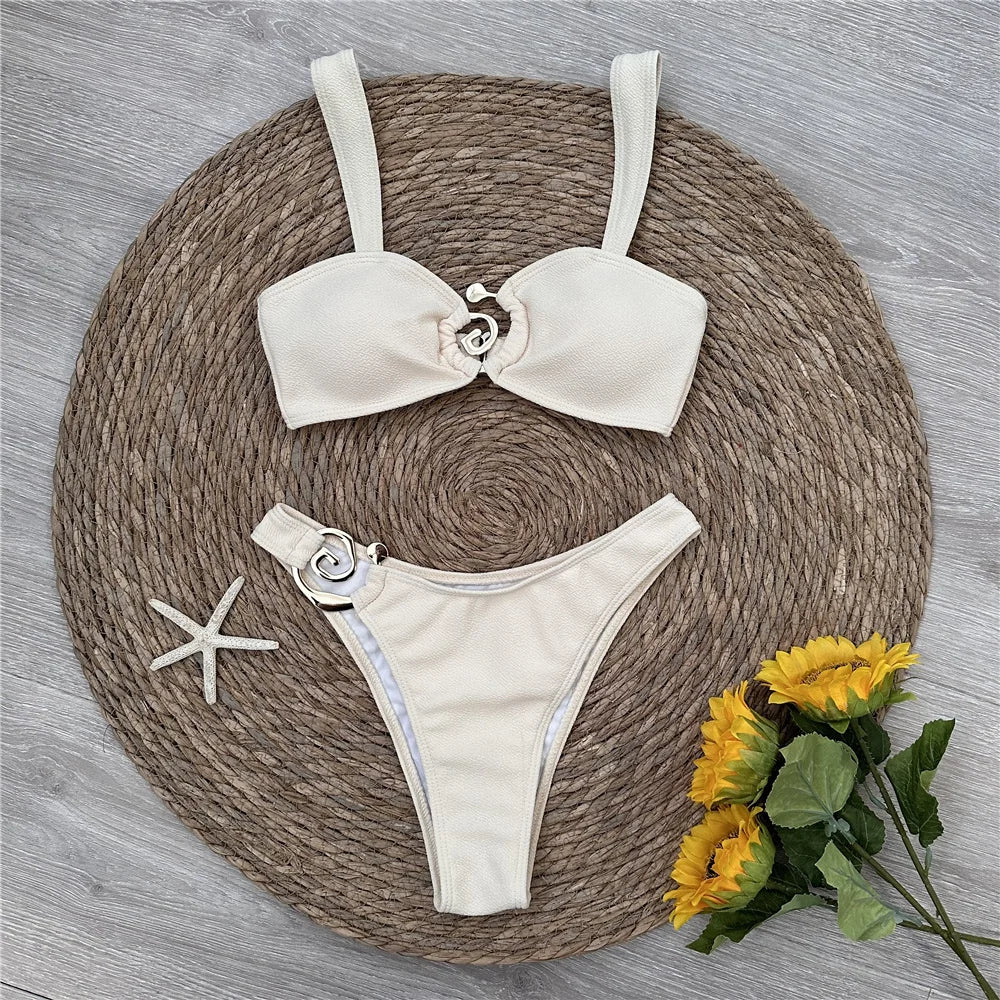 White bikini set with bow design on a woven mat with flowers and starfish.