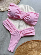 Pink bikini set on a textured surface with woven mat