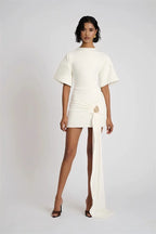 Woman wearing a white outfit with a flowing skirt on a plain background