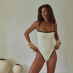 Woman wearing a white swimsuit with black trim against a plain background