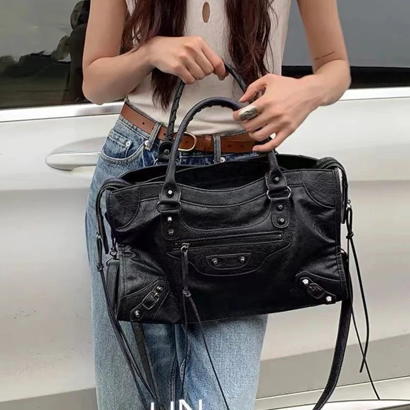 Person holding a black handbag with a blurred background