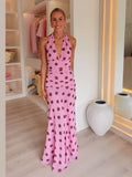 Woman wearing a pink dress with purple polka dots in a room.
