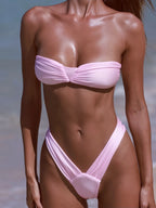 Person wearing a pink bikini set on a beach.