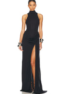 Woman wearing a black halter neck gown with a high slit on a white background