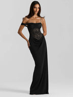 Woman wearing a black evening gown with lace detailing on a light gray background