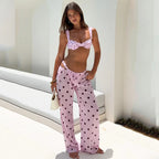 Woman wearing a pink polka dot bikini and pants against a white background