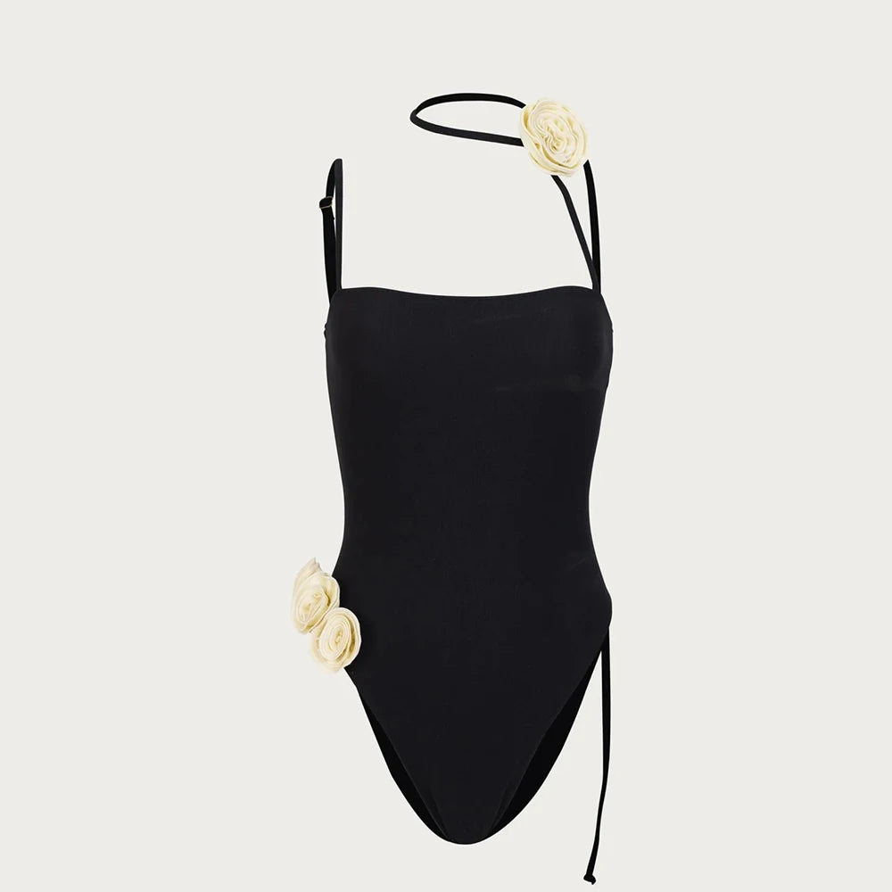 Black swimsuit with floral details on straps against a light gray background