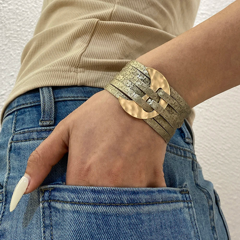 Person wearing a gold bracelet on a neutral background