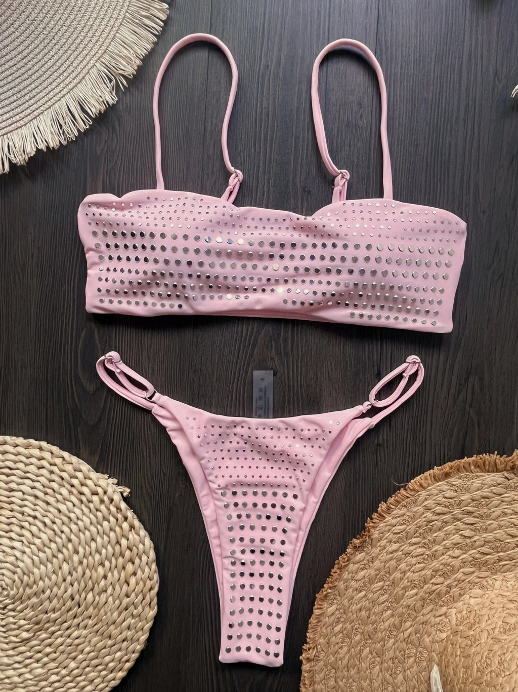 Pink bikini set on a dark surface with woven circular objects.