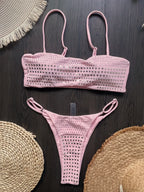 Pink bikini set on a dark surface with woven circular objects.