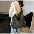 Person carrying a leopard print bag in an indoor setting