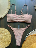 Pink bikini set on a dark wooden surface with decorative mats.
