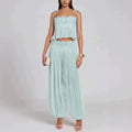 A woman models a light mint green two-piece set consisting of a lace-trimmed crop top with ruffles and matching pleated harem pants, against a plain light gray studio background.