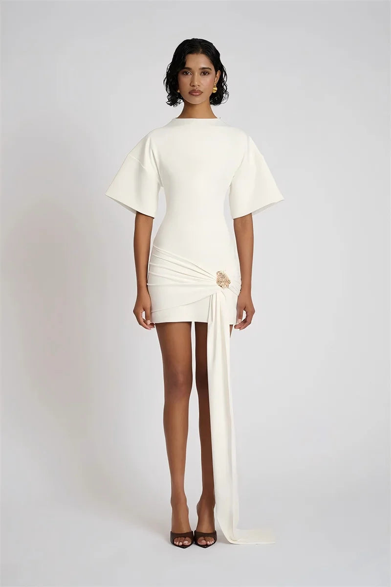 Woman wearing a white dress with a slit on a plain background