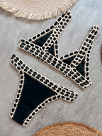 Black bikini set with beige accents on a gray surface