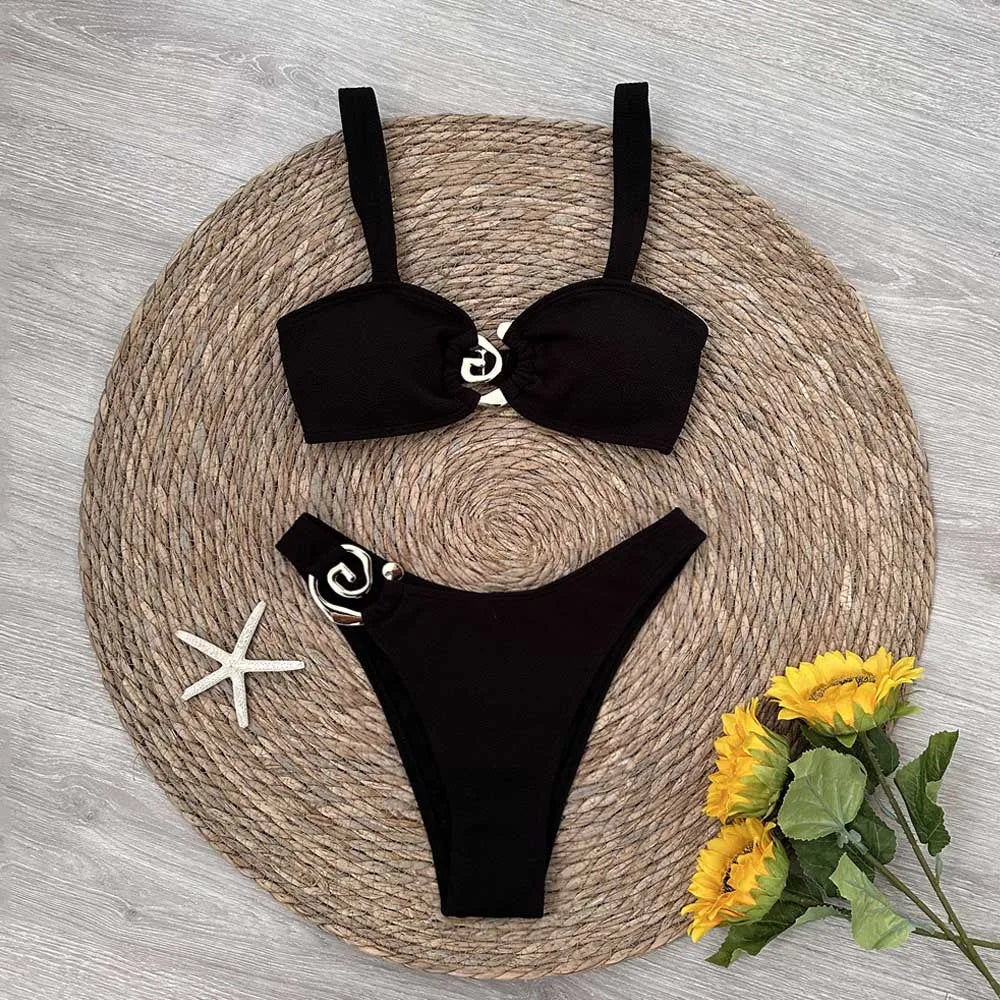 Black bikini set on a woven mat with sunflowers and a starfish