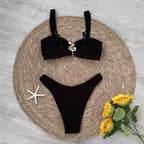 Black bikini set on a woven mat with flowers and a starfish