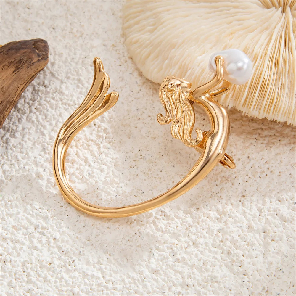 Gold bracelet with a pearl on a textured beige surface