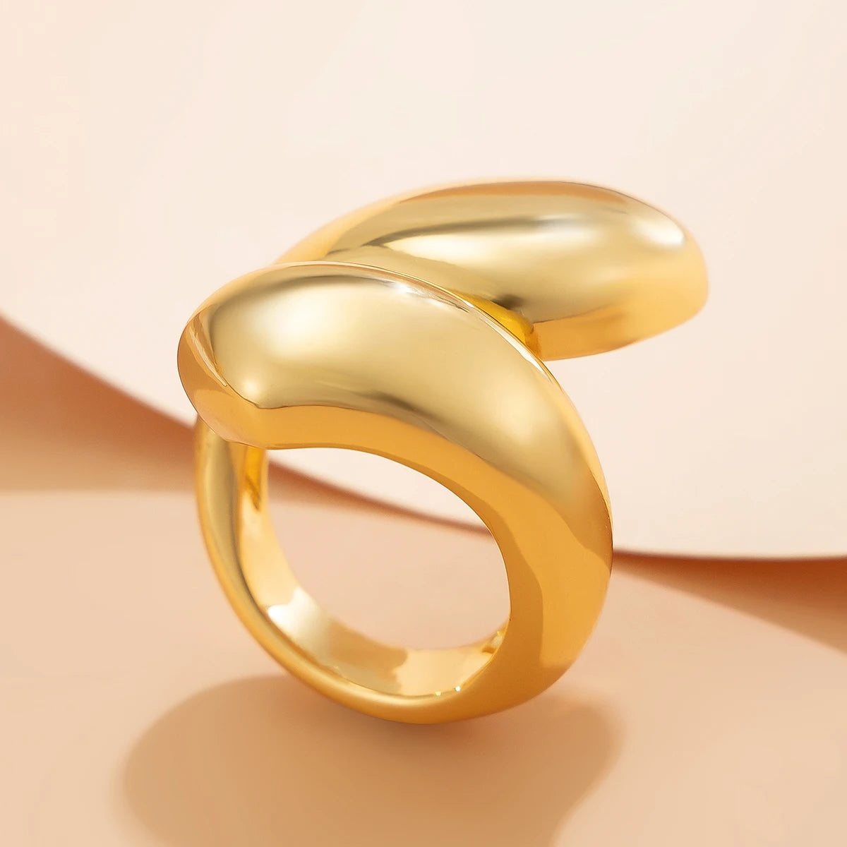 Gold ring with a twisted design on a beige background