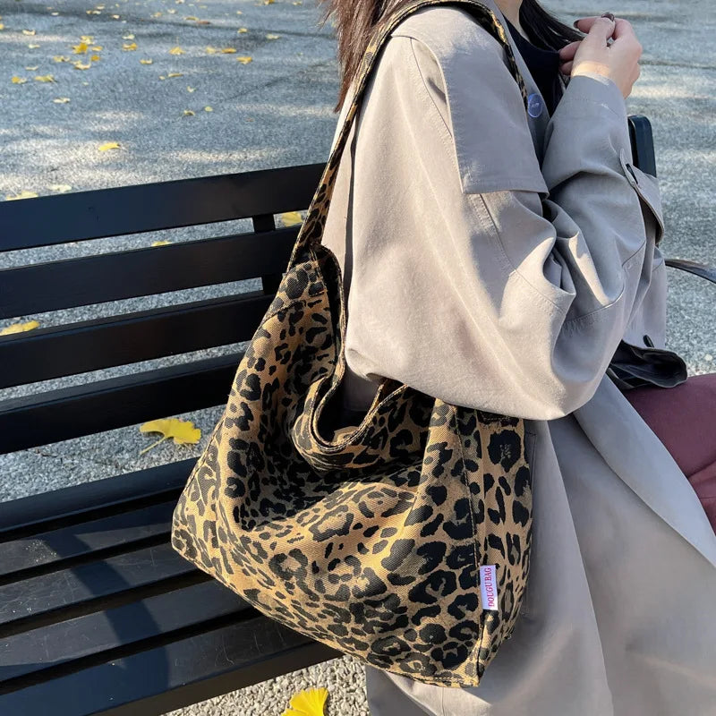 Person holding a leopard print bag outdoors on a bench