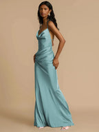 A woman wearing a blue maxi dress with lace back detail, standing against a neutral background.