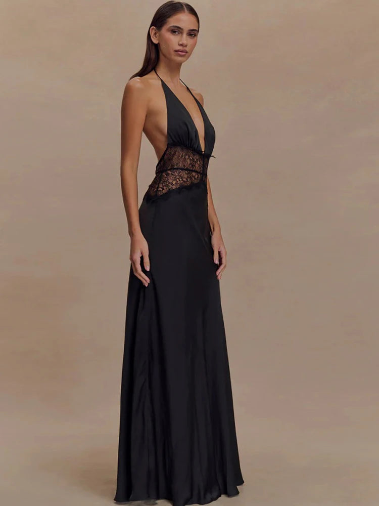 Woman wearing a black evening gown with lace detailing on a beige background