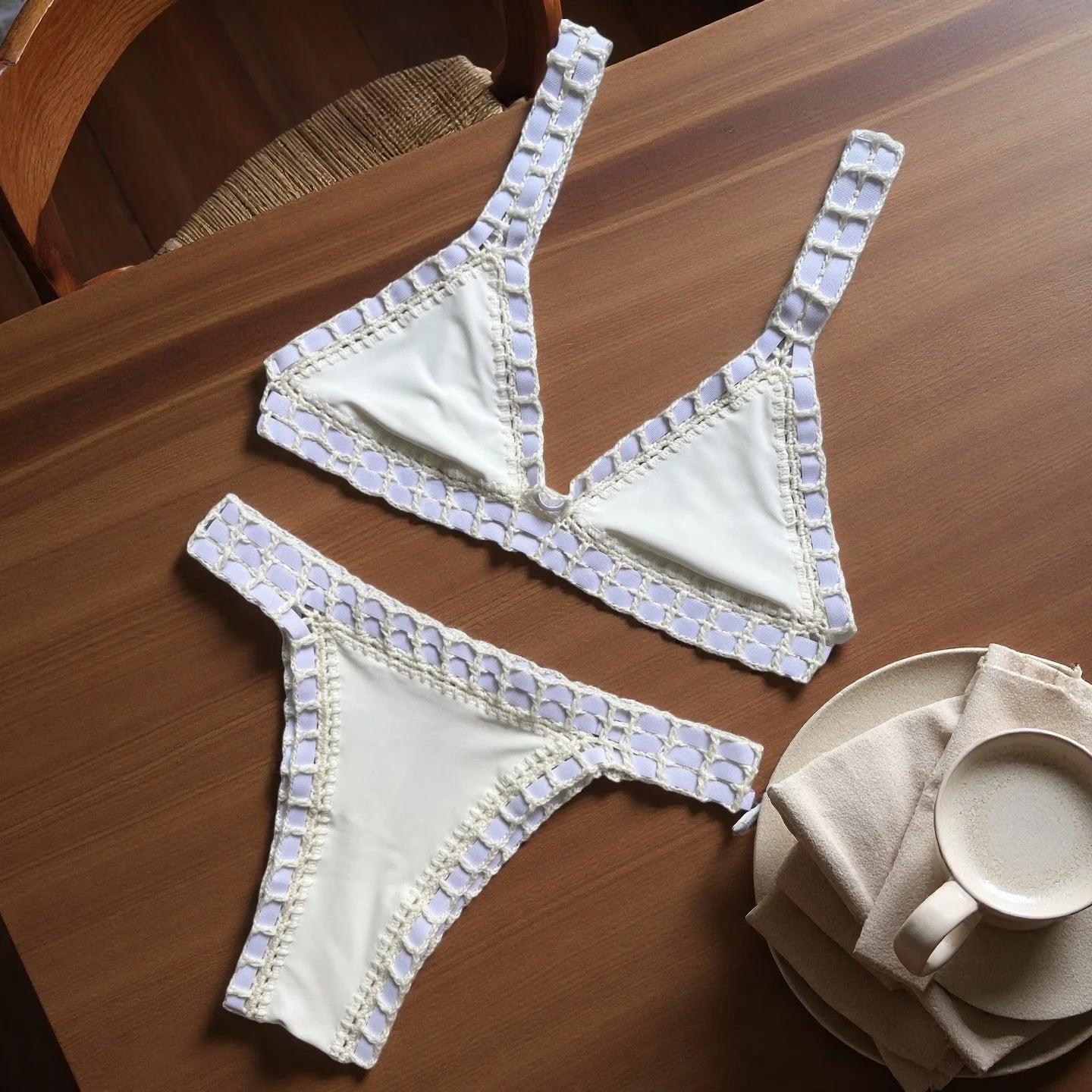 White bra and panties set with decorative trim on a wooden table.