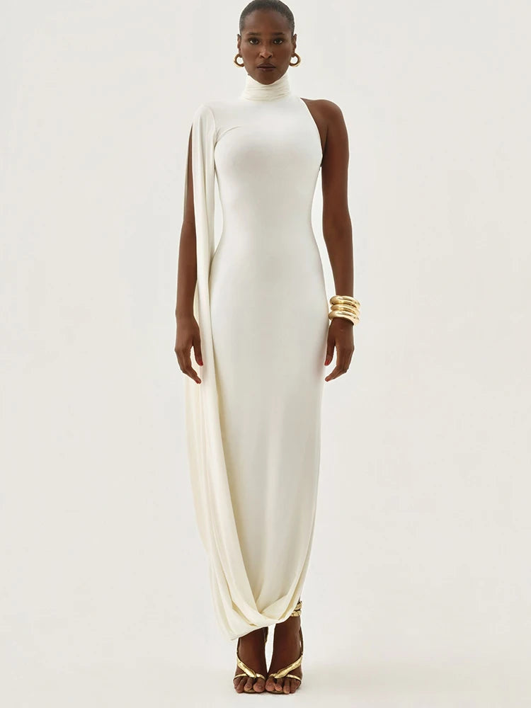 Woman wearing a white dress with gold accents on a plain background