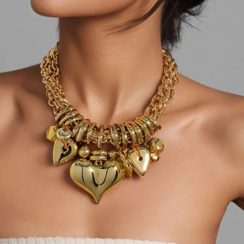 Gold necklace with heart-shaped pendants on a person against a neutral background