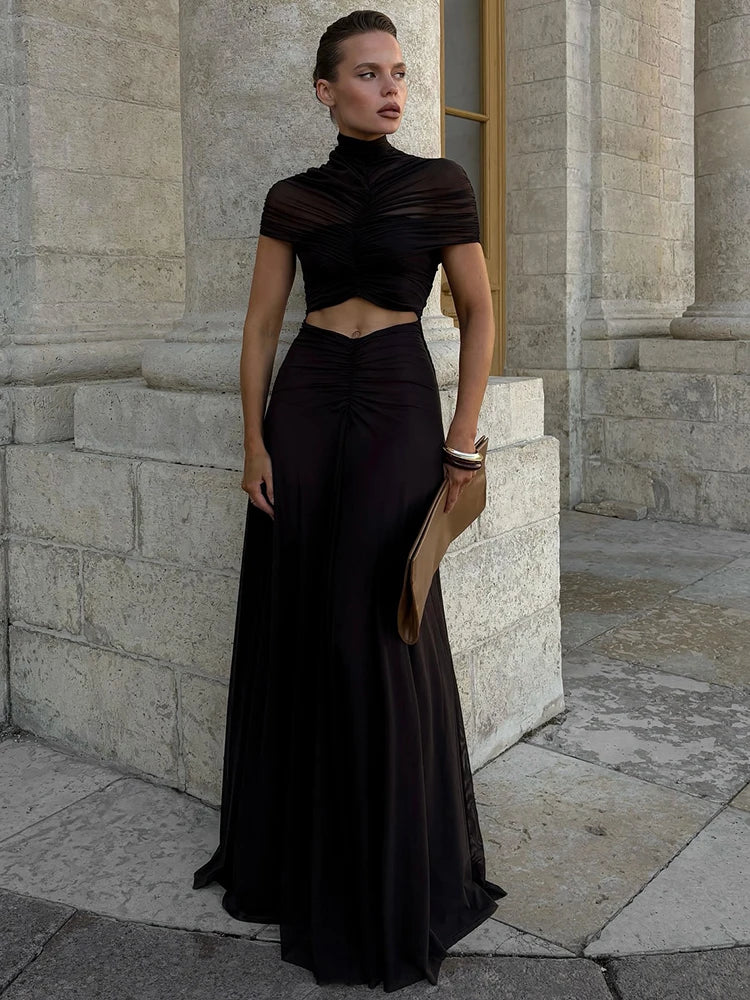 Woman in a black dress standing in front of a stone building