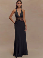 Woman wearing a black evening gown with a deep neckline and embellished belt on a beige background