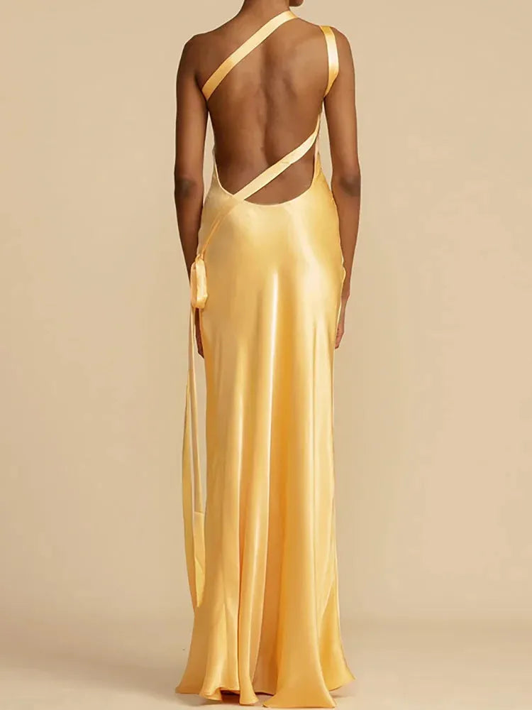 Gold evening gown with open back on a plain background