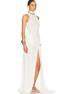Woman wearing a white halter neck gown with gold accessories on a white background