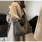 Person wearing a beige coat with a leopard print bag in an indoor setting
