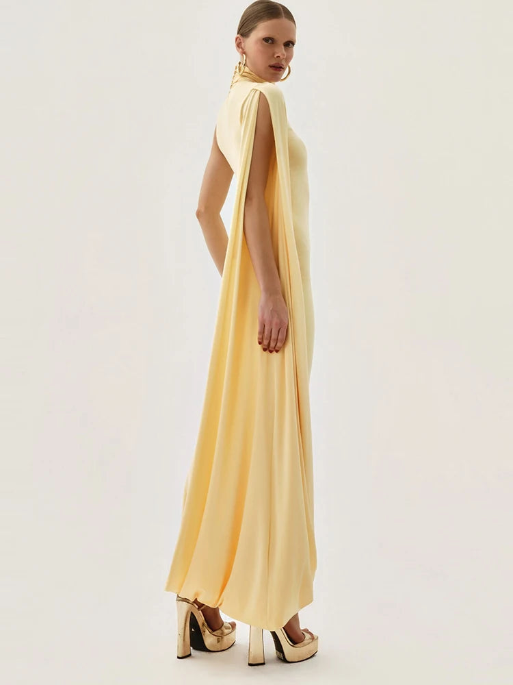 Woman wearing a yellow evening gown with a cape on a white background