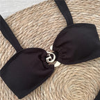 Black bikini top with a silver clasp on a woven surface