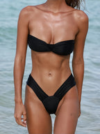 Person wearing a black bikini set with a blurred water background