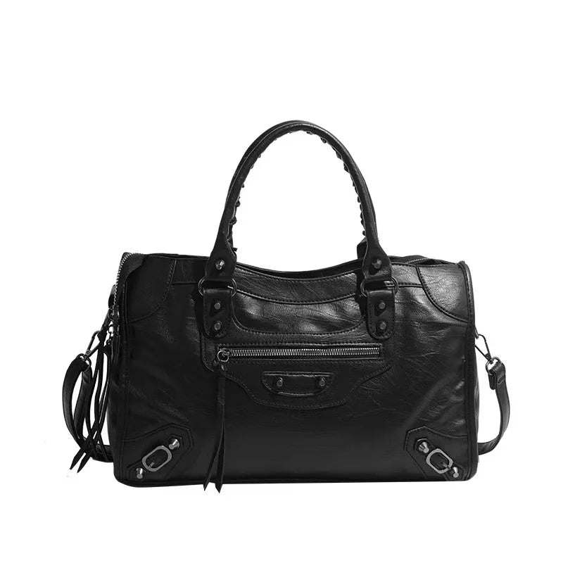Black leather handbag with multiple zippers on a white background