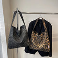 Two tote bags with leopard print design hanging on a rack.