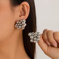 Silver bead earrings being worn and held by a person against a neutral background