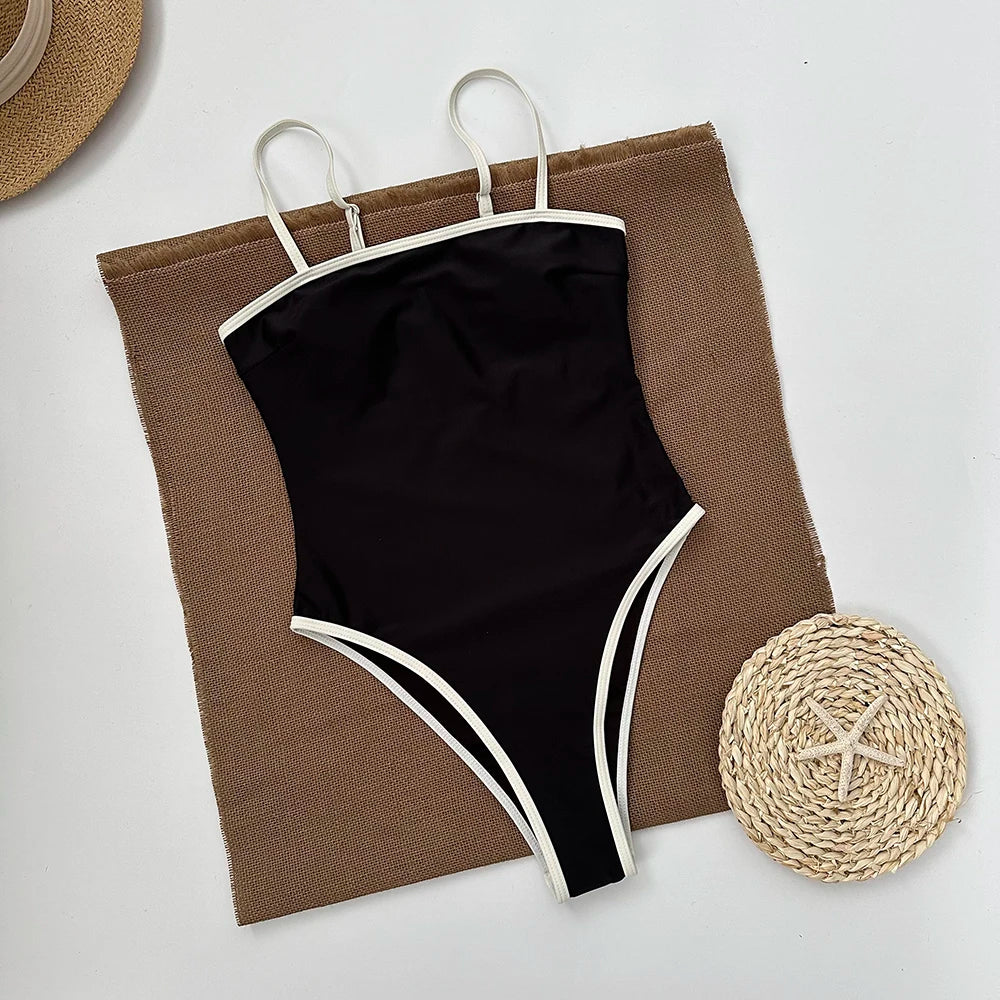 Black swimsuit with white straps on a brown mesh bag with a white background