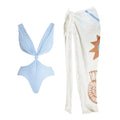 Light blue bikini top and white sarong with shell patterns on a white background