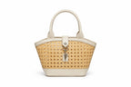 A structured handbag with a woven natural cane body and cream-colored faux leather trim, featuring dual top handles and a front turn-lock clasp with a hanging key charm, shown on a plain white background.