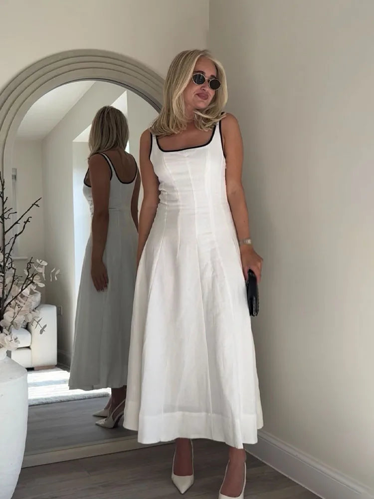 Woman in a white dress standing in front of a mirror in a room.