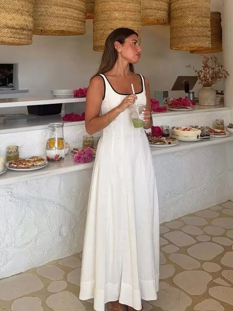 Woman in a white dress standing in a kitchen with wicker pendant lights.