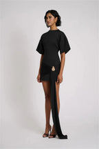 Woman wearing a black dress with a slit on a white background