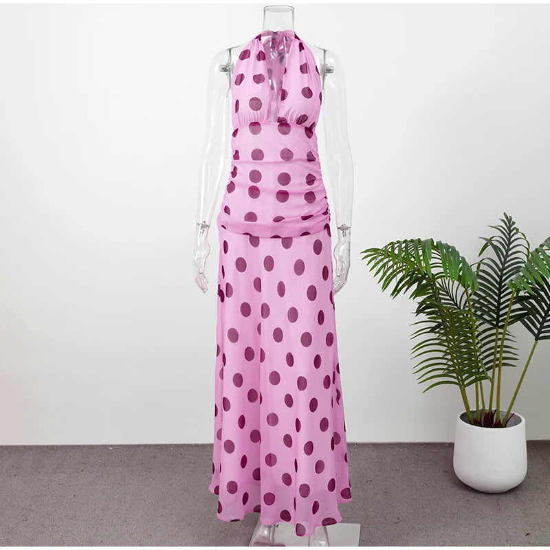 Pink polka dot dress on a mannequin with a plant in the background