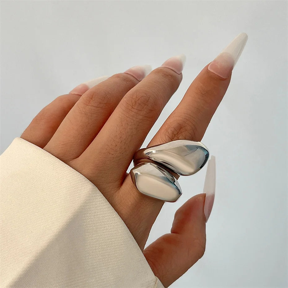 Hand wearing a silver ring with a plain background